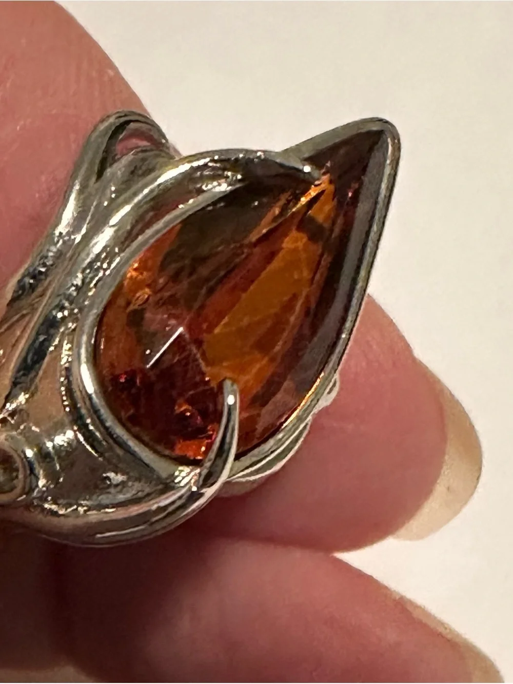 Ring in silver metal intricate with teardrop shaped amber color stone